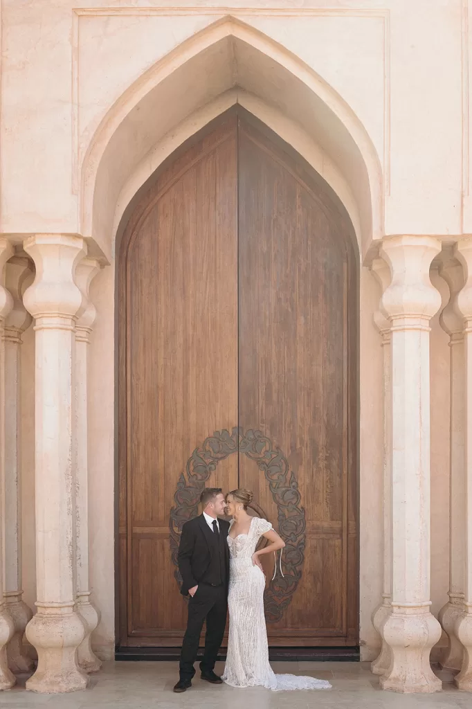 Bride and groom sharing a quiet moment beneath grand carved doorway at Palais Namaskar