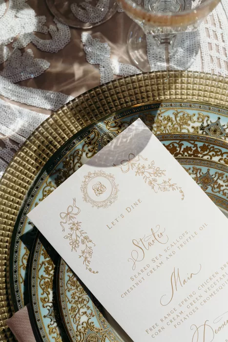 Elegant wedding table setting with ornate gold-rimmed plates and printed menu at Palais Namaskar