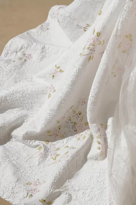 Close-up of embroidered bridal gown fabric with delicate floral details
