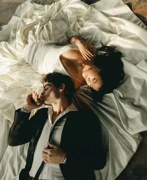 The couple rest in warm light, surrounded by the bride’s softly draped gown.