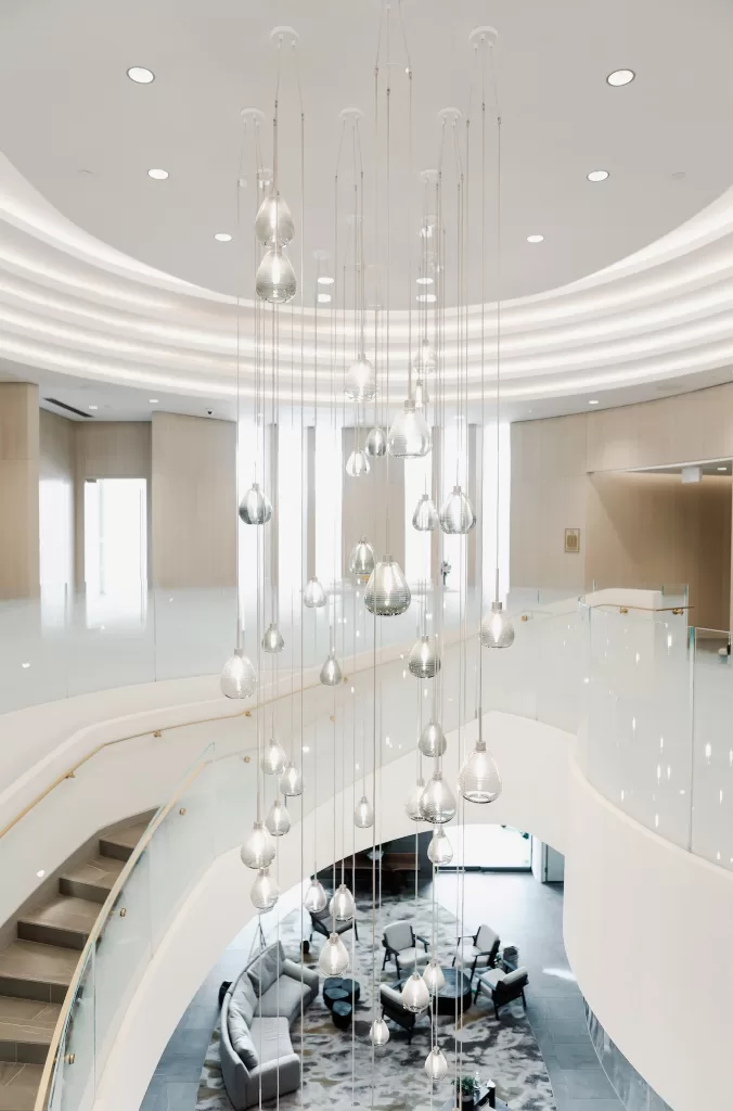 Sculptural chandelier hanging above the bright curved lobby staircase.