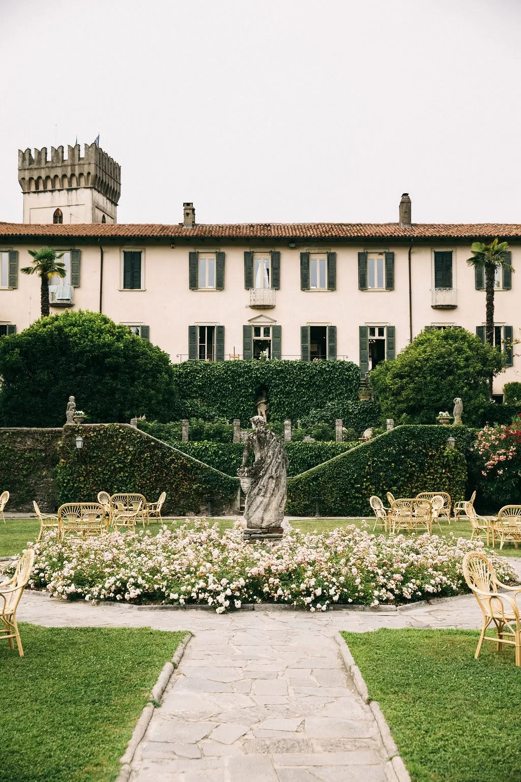 Stone statue surrounded by roses in the gardens of Villa Bossi.