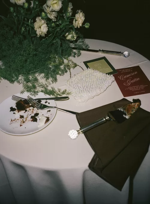 Wedding stationery, cake plates and pearl bag styled on a reception table