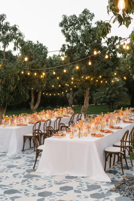 Outdoor reception tables at Acre Baja glowing under string lights and trees.