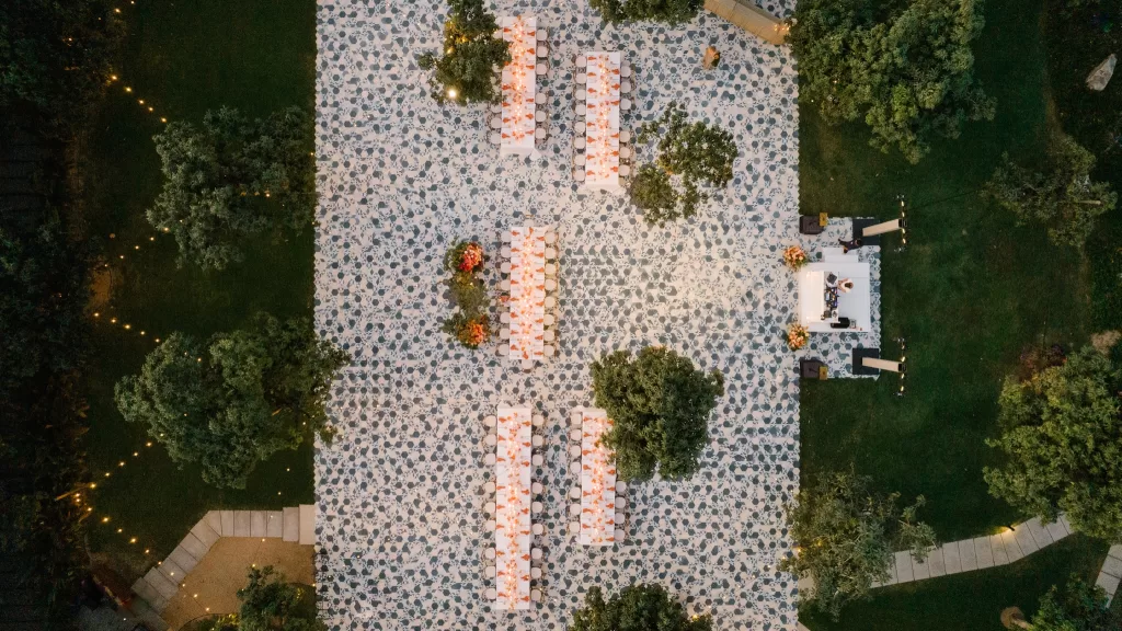Overhead view of long reception tables arranged across a patterned outdoor terrace.