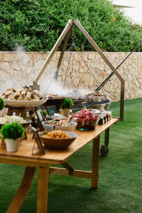 Outdoor grill and buffet table set on the lawn for a relaxed wedding meal.