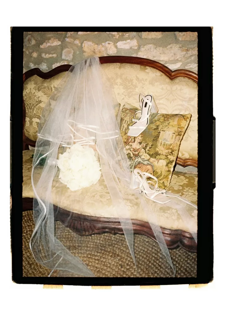Veil, bouquet, and heels arranged on antique sofa, softly lit with a romantic feel