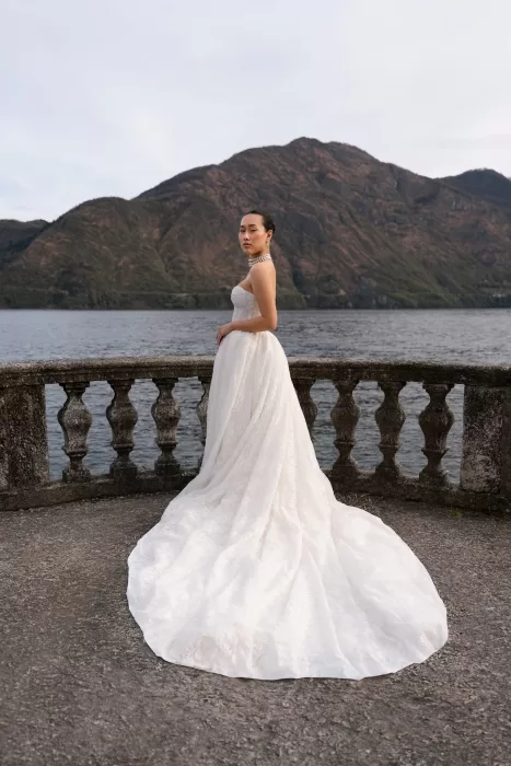 Bride posing by the stone balustrade, her lace gown sweeping toward Lake Como.