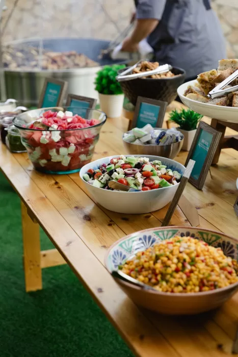Colourful Mediterranean buffet with salads, breads, and sharing dishes on a wooden table.