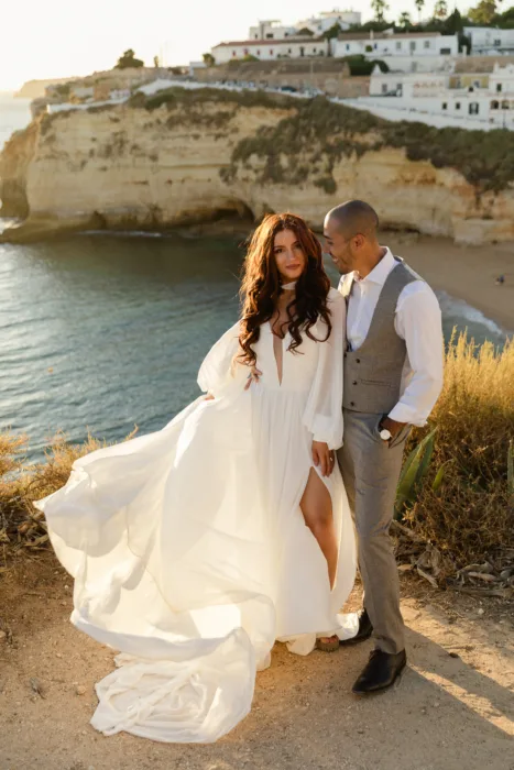 Newlyweds posing on the cliffs overlooking the Algarve coastline at golden hour