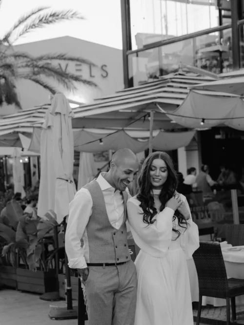 Black and white portrait of the bride and groom walking through an evening street in the Algarve
