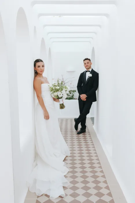 The couple pose apart in Casa Arte’s bright arched corridor with patterned floor tiles.