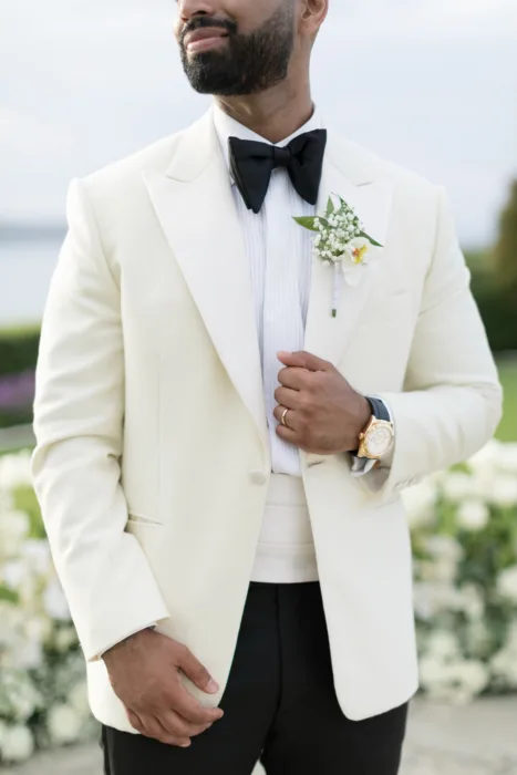 Groom in a cream tuxedo with black bow tie and white orchid boutonniere.