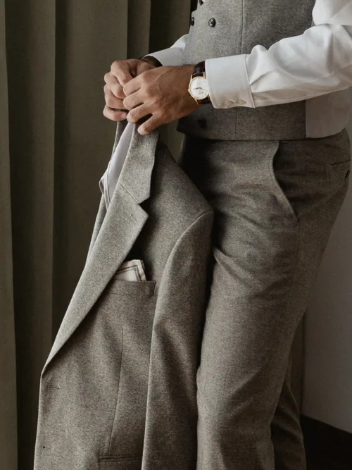 Groom holding his light grey wedding jacket while getting ready
