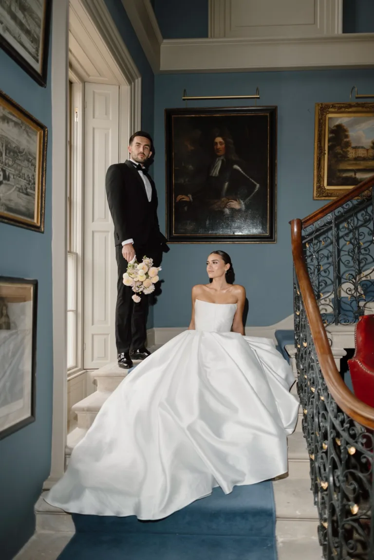 Bride and groom posing on the grand staircase inside Hotham Hall.