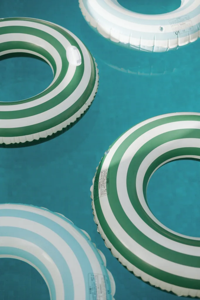 Striped pool floats drift across bright turquoise water beside the villa.