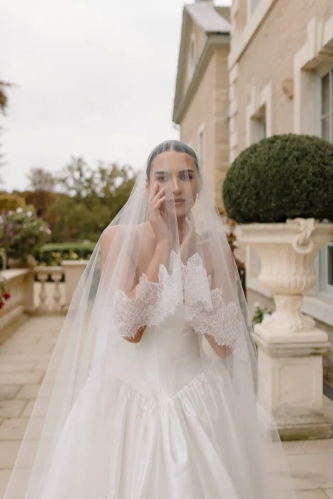 Bridal portrait with a cathedral veil and lace gloves on the terrace at Hotham Hall.