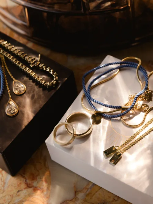 Wedding rings and gold jewellery arranged in warm natural light before the ceremony