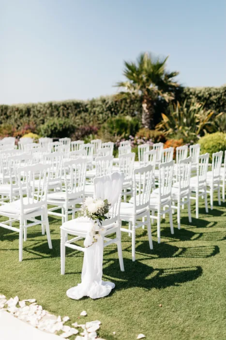 White ceremony chairs arranged on the lawn with floral aisle details.