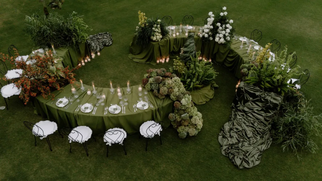 Aerial view of a sweeping spiral table edged with white chairs, hydrangeas and pooled olive satin