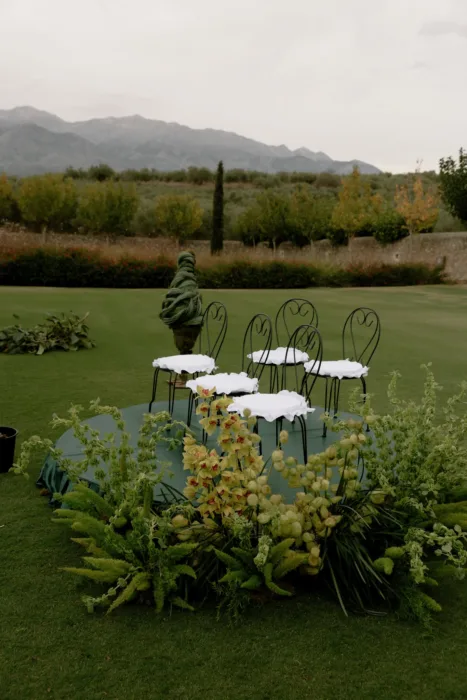 Ceremony chairs on a raised platform framed by orchids and ferns, the mountains of Crete beyond