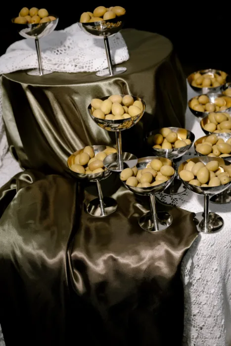 Polished silver coupes of olives glowing against dark satin, lit like an old-master still life