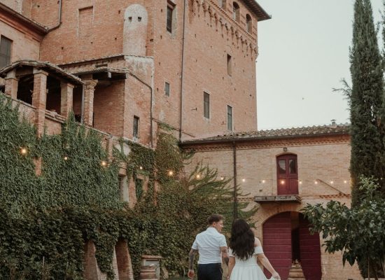 The bride and groom standing together against the breathtaking backdrop of Castello di San Fabiano's estate, photographed by Bella Weddings.