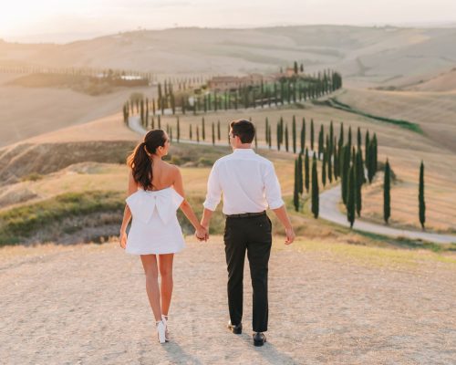 Newlyweds embracing on a mountain, with a vast landscape behind them