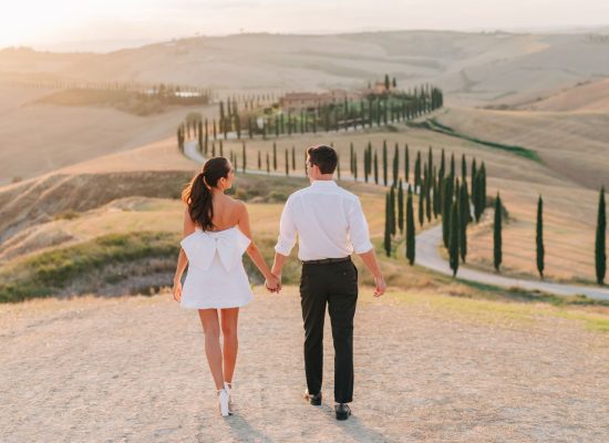 Newlyweds embracing on a mountain, with a vast landscape behind them