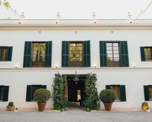 Stunning main exterior view of Masia Aldamar, a picturesque Spanish wedding venue surrounded by lush greenery.